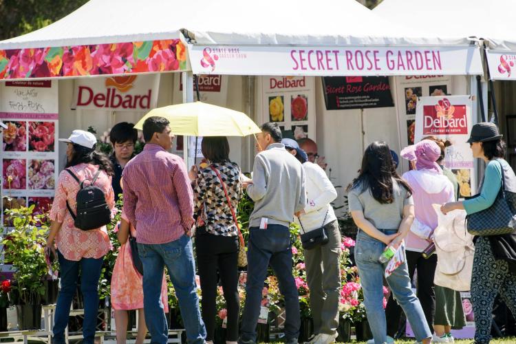 people gathered in front of a marquee with gardening items for sale